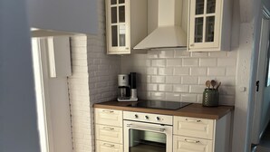 A compact kitchen with white cabinetry, a built-in oven, and a coffee maker on the countertop. - Stork's nest apartment (Steinburg)