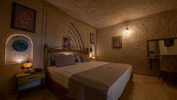 Une chambre à coucher comprenant un lit, une table de chevet, une lampe, un miroir et un mur orné d’un motif texturé.