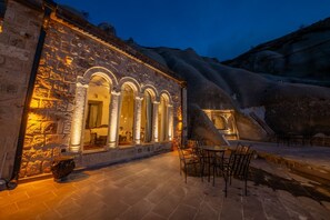 A stone building with arched windows and a patio area with chairs. - Majestic Cave House (Nevsehir)
