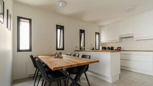 Una cocina moderna con armarios blancos, una mesa de comedor de madera y sillas negras.