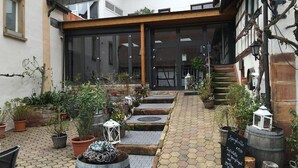 A courtyard with potted plants, a stone pathway, and a signboard.