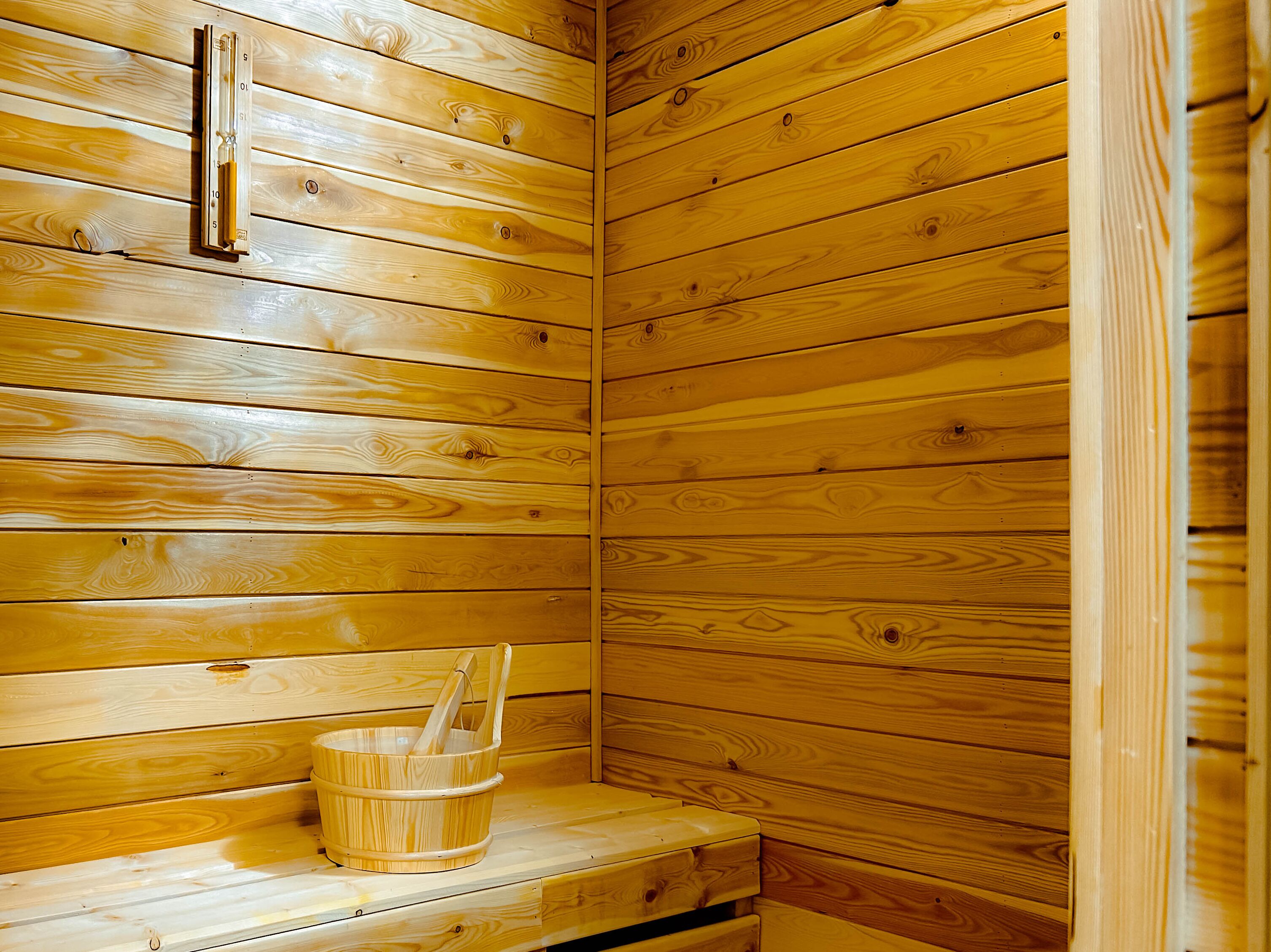 A wooden sauna with a wooden bench and a bucket.