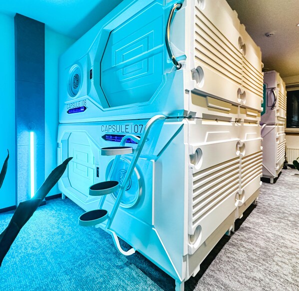 A room with a large, white, futuristic-looking capsule labeled "Capsule 107" and a smaller "Capsule 108". - UBPOD capsule hotel in Mongolia (Ulaanbaatar)