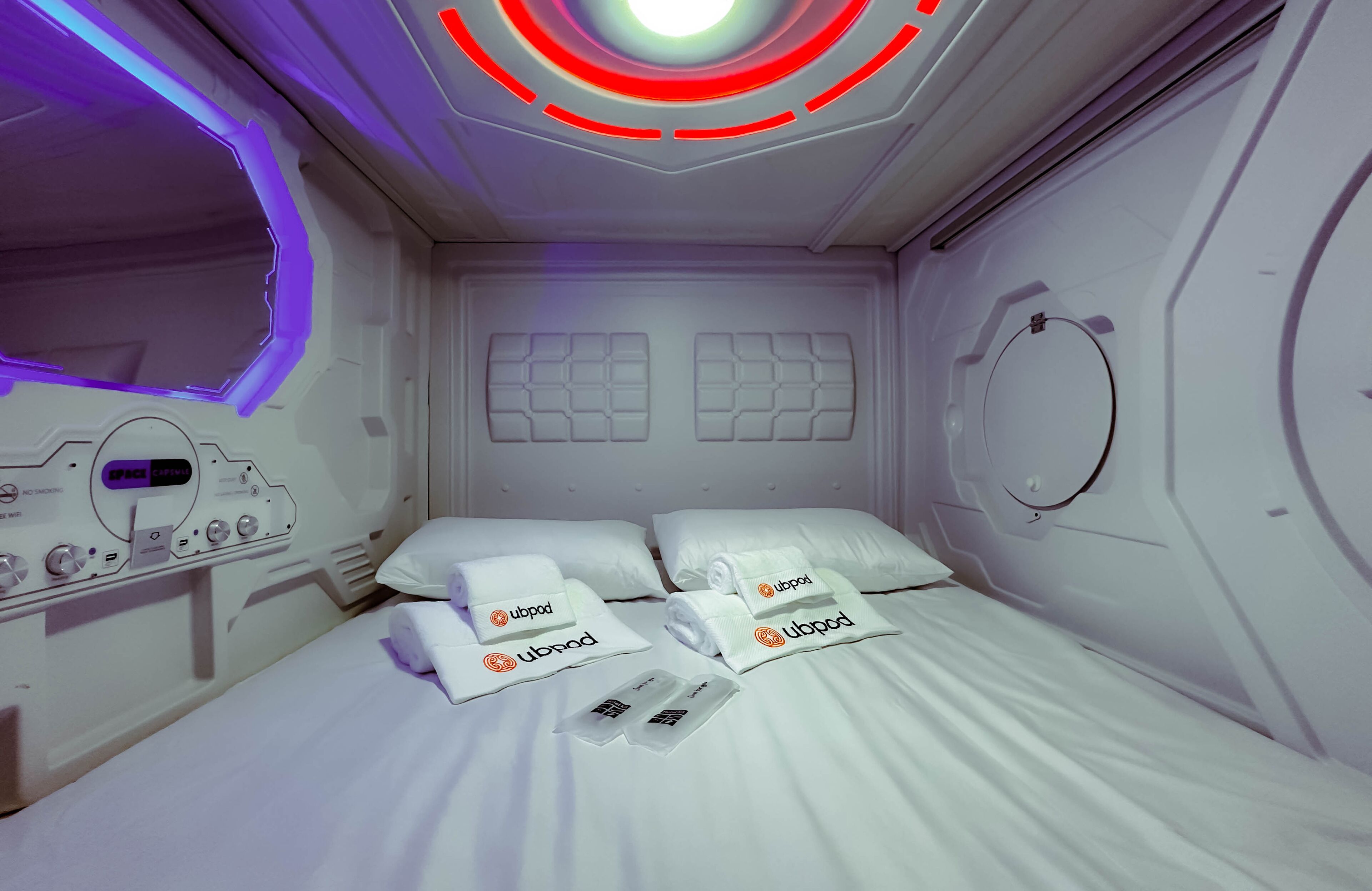 Una habitación de hotel moderna con cama, almohadas y un panel de control.