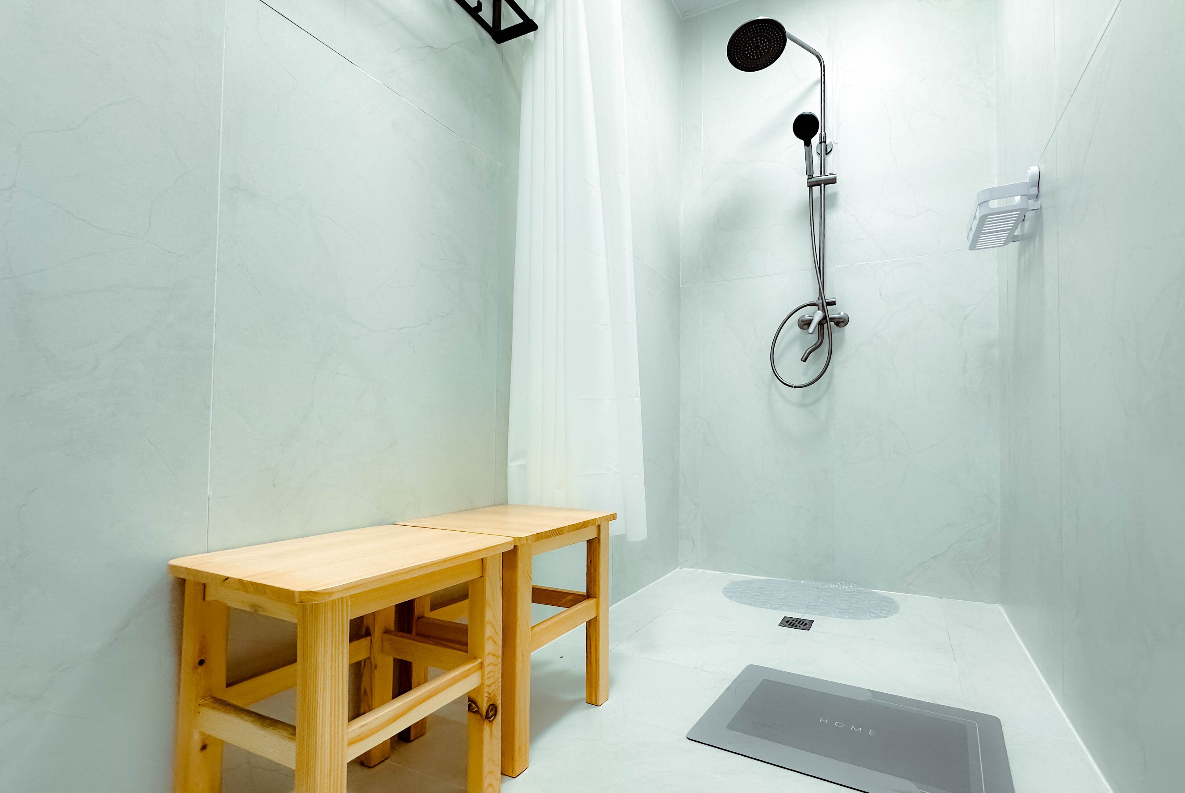 Un baño pequeño y moderno con ducha, un taburete de madera y una mesita.