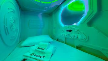 A medical treatment room with a bed, a control panel, and a green-lit ceiling.