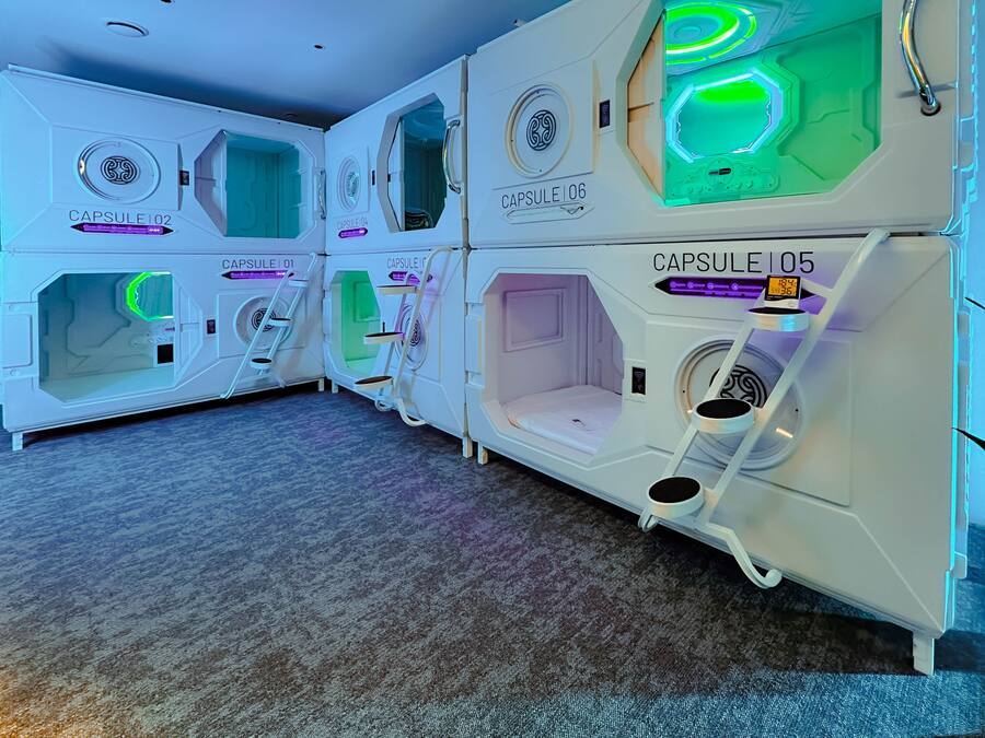 A row of capsule hotel rooms with individual doors, each labeled with a capsule number.