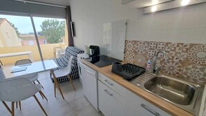 Et kompakt køkken med vask, kaffemaskine og et mønstret backsplash.