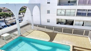 A rooftop pool with a clear blue water surface, surrounded by a white fence and a gravel area. - Air-conditioned apartment for 4 with pool, terrace and sea view (Le Barcarès)