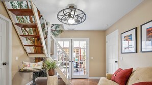 A living room with a wooden staircase, a ceiling fan, and a view of the outside.
