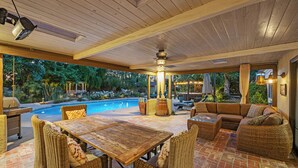 An outdoor patio area with a pool, wicker furniture, and a ceiling fan.