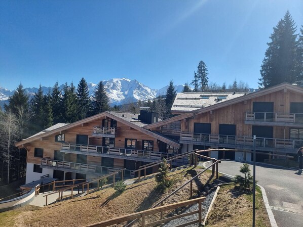 A wooden chalet with a balcony and a ski lift in the background.