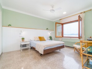 A bedroom with a bed, bedside table, chair, window, and radiator.