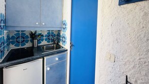 A kitchen with blue cabinets, a sink, and a door with a blue handle.