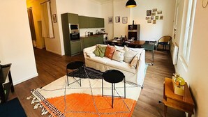 Un espace de vie compact comprenant une cuisine, un coin repas et un canapé agrémenté d’un tapis à motifs.