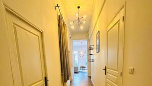 Un couloir étroit doté d’un plancher en bois, de portes blanches et d’un tapis à motifs.