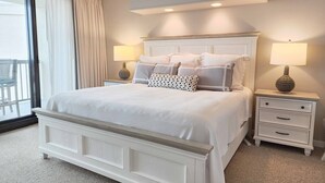 A bedroom with a large bed, two bedside tables, and a view of the balcony. - Crescent D4E Litchfield Beach (Pawleys Island)