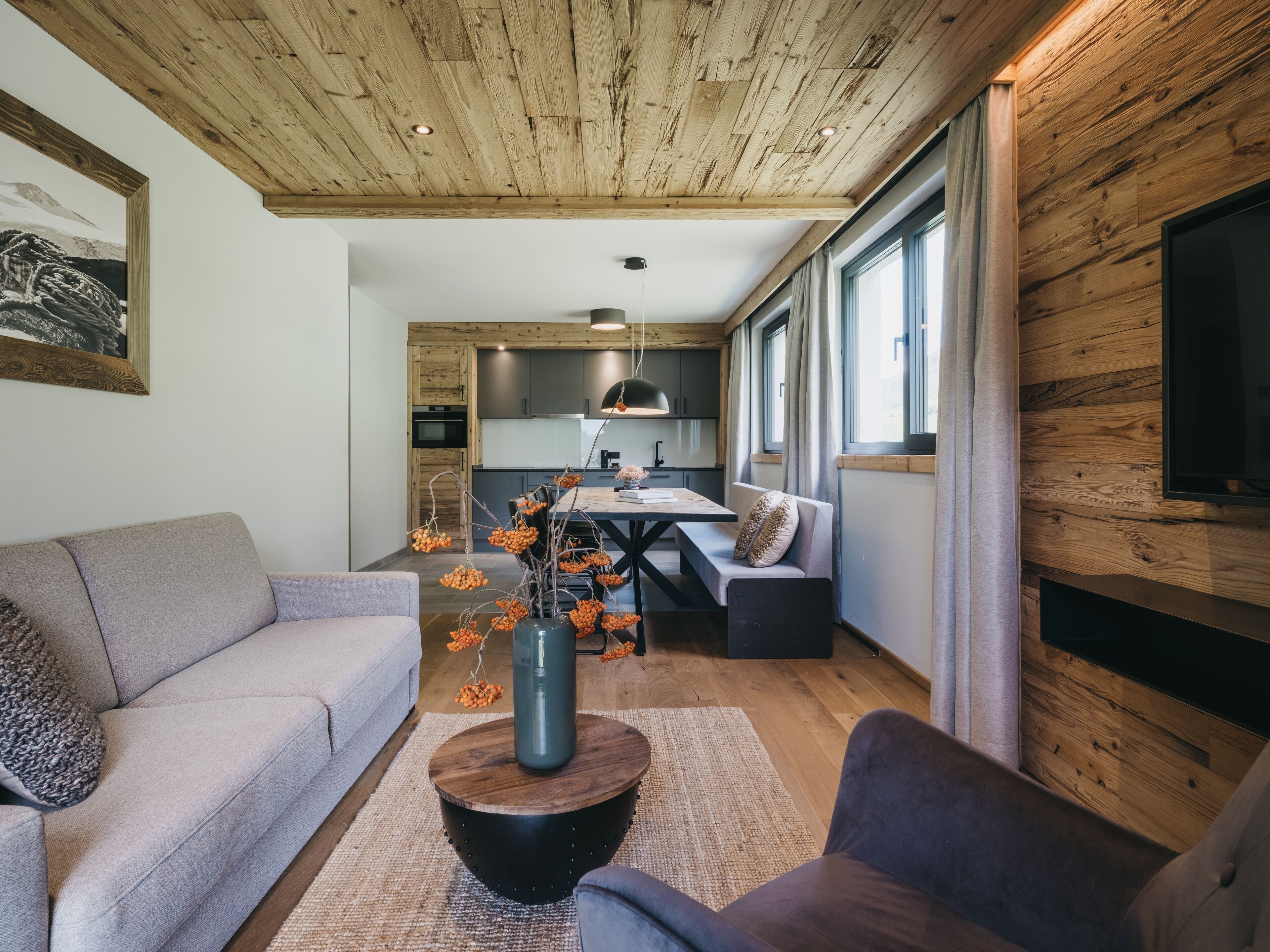 Una sala moderna con un sofá, una mesa de centro con un florero, y un comedor con una mesa y sillas.