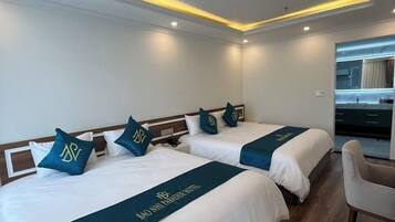 Habitación de hotel con dos camas, cada una con cabecera y almohadas a juego, y un escritorio con silla.