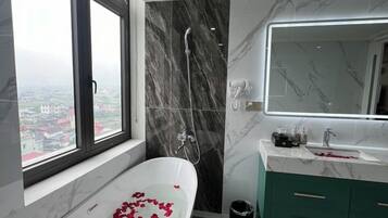 A modern bathroom with a freestanding bathtub, a large mirror, and a view through a window.