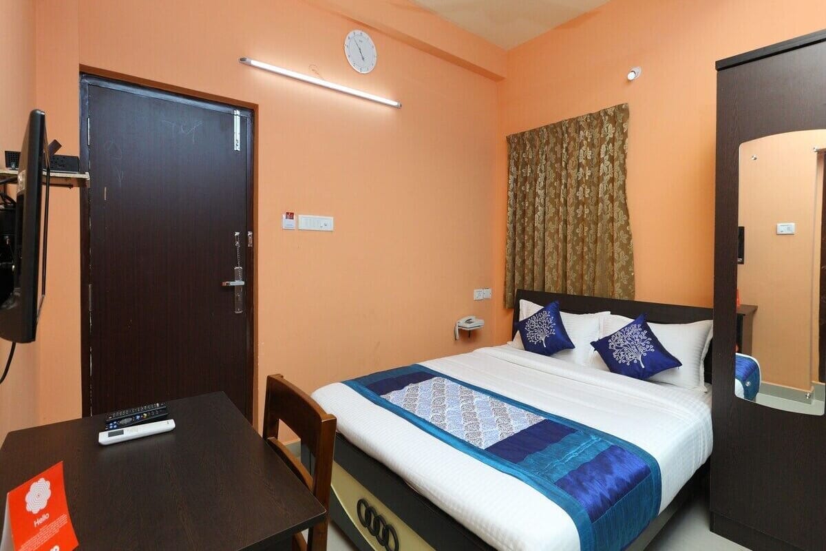 Une chambre d’hôtel avec un lit, un bureau, une chaise, une horloge et une porte.