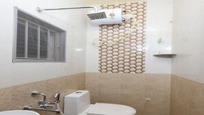 Een badkamer met toilet, wastafel, douche en een raam.