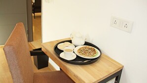 Een eettafel met een dienblad waarop een theepot, kopjes en een bord eten staan.