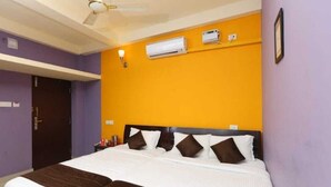 Een hotelkamer met een bed, een airconditioning, een plafondventilator en een deur.