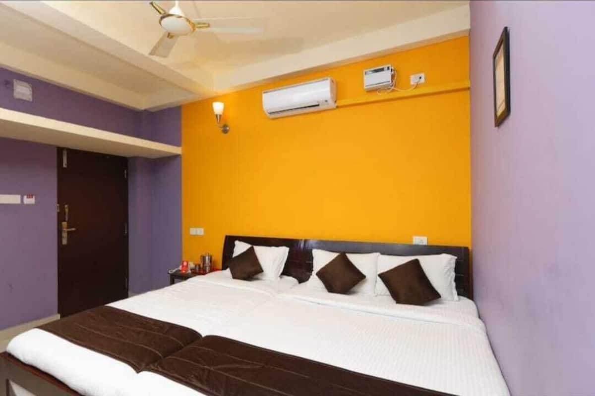 Une chambre d’hôtel équipée d’un lit, d’un climatiseur, d’un ventilateur de plafond et d’une porte.
