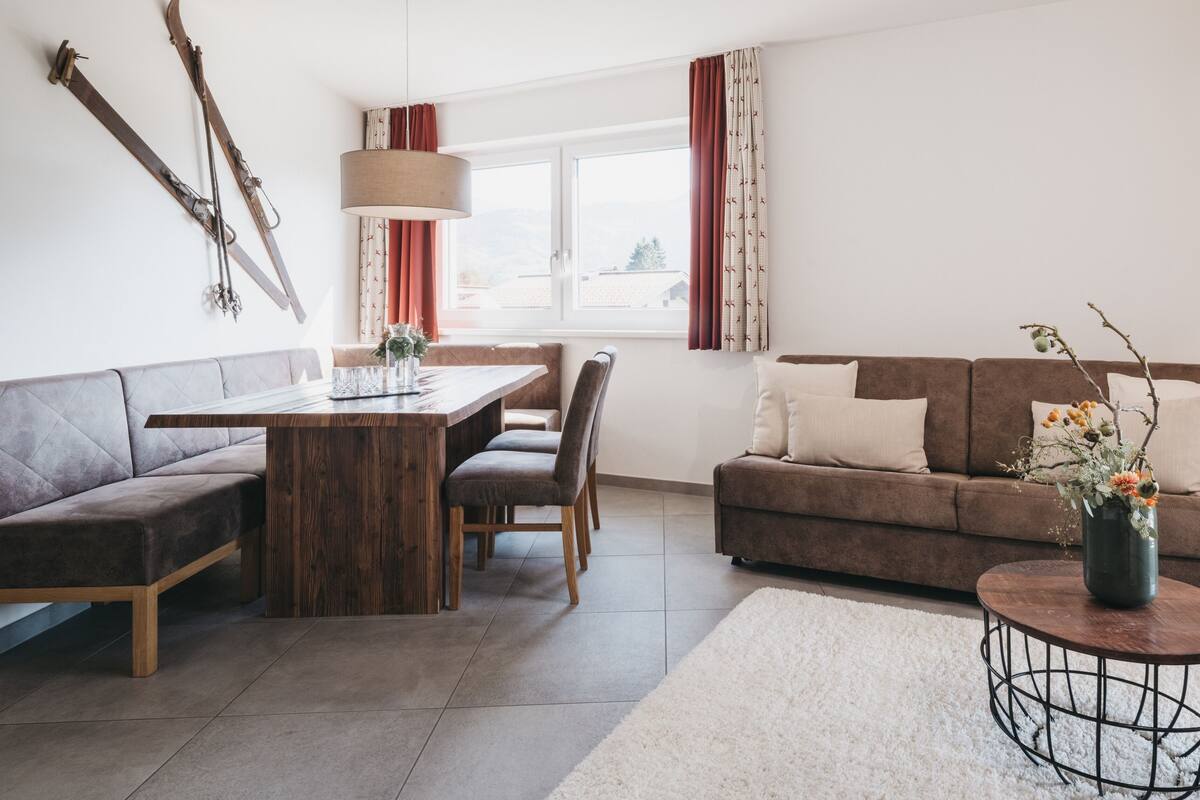 Una sala de estar moderna con una mesa de comedor de madera, dos sofás y una mesa de centro.