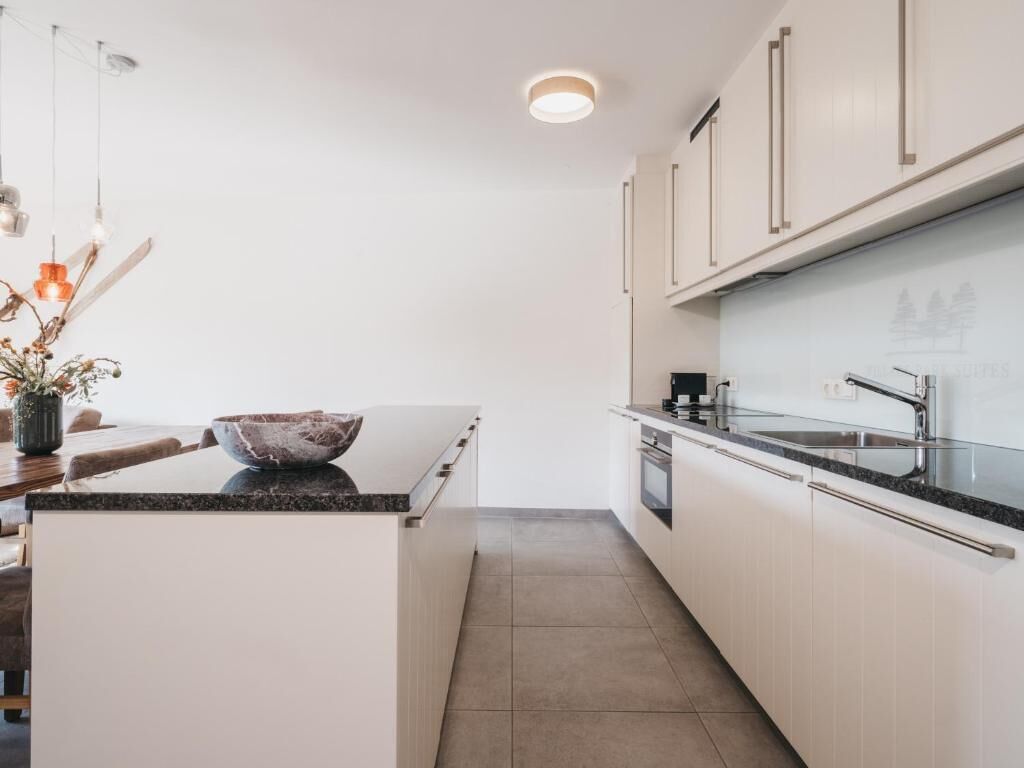 Eine moderne Küche mit weißen Schränken, einer Granitarbeitsplatte und einem eingebauten Backofen.