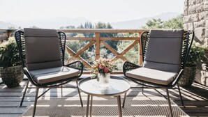A wooden deck with two cushioned chairs and a small table with a vase of flowers. - Village Park Suites (Zell am See)