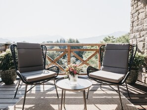 Eine Holzterrasse mit zwei gepolsterten Stühlen und einem kleinen Tisch mit einem Blumenstrauß.