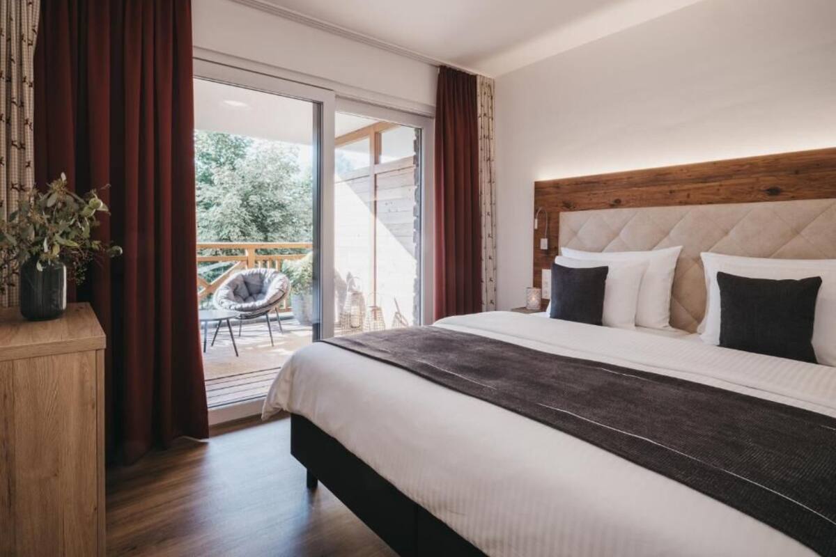 Un dormitorio con una cama grande, cabecera de madera y vistas al exterior a través de una puerta corredera de vidrio.