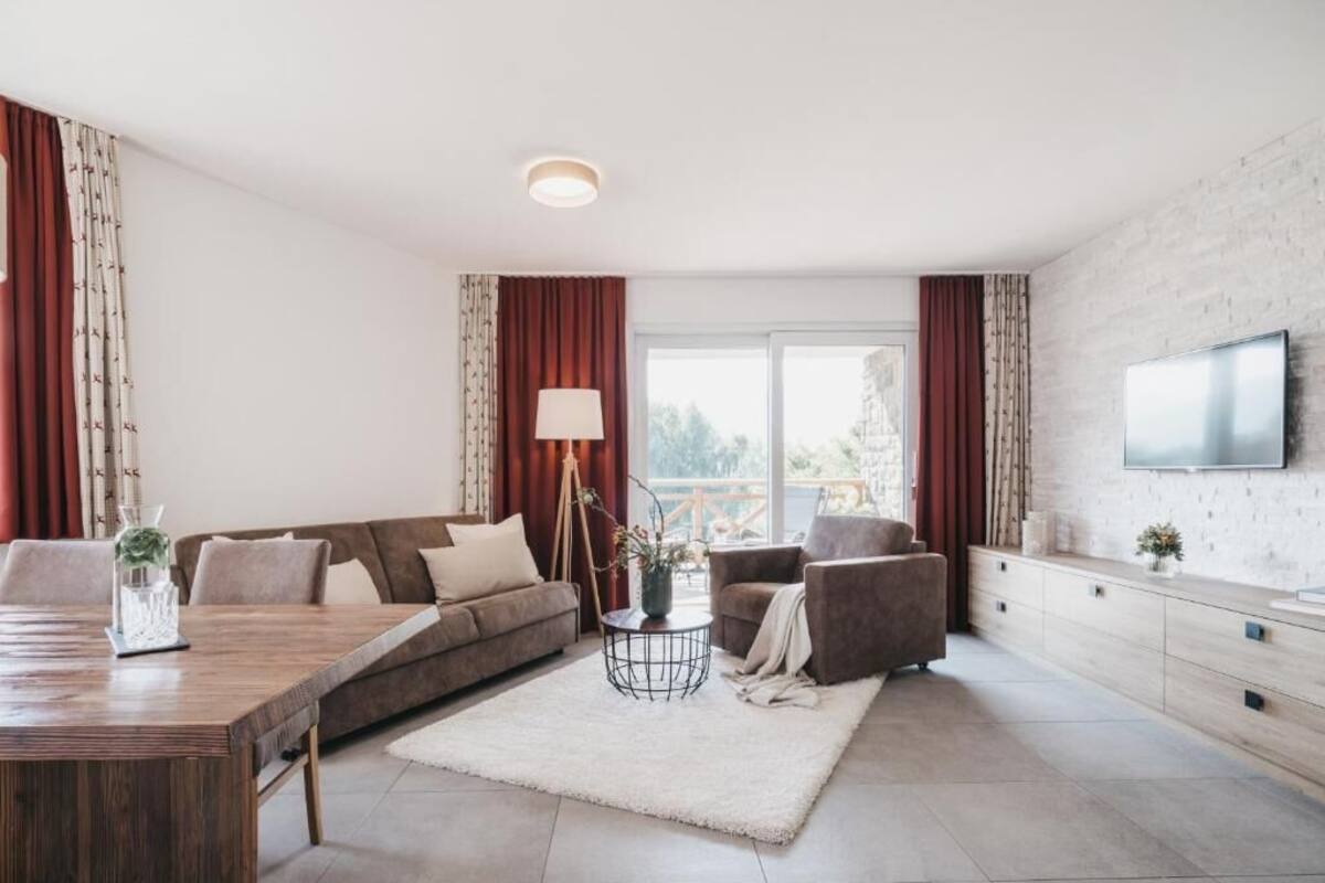 Una sala moderna con sofá, sillones, una mesa de centro y un televisor montado en la pared.