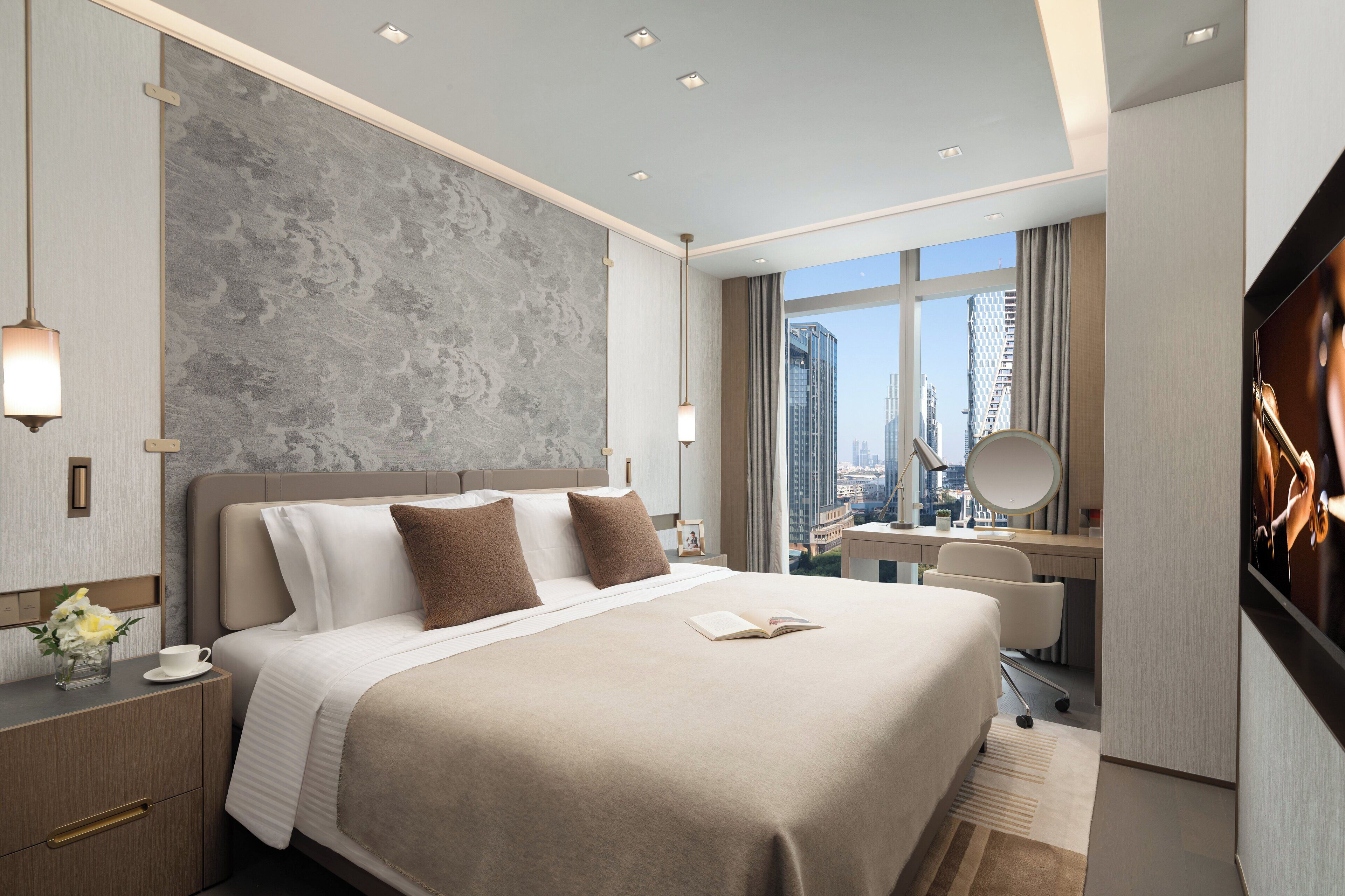 Una habitación de hotel moderna con una cama grande, un escritorio, una silla y vistas de la ciudad a través de la ventana.