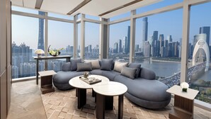 A modern living room with a large sectional sofa, two round coffee tables, and a view of a cityscape through large windows.