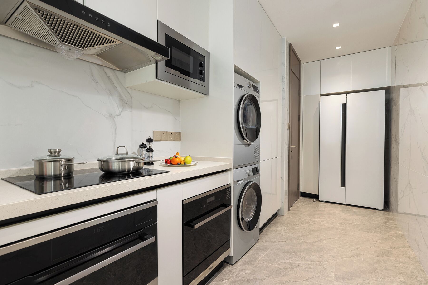Une cuisine moderne équipée d’une cuisinière, d’un four, d’un four à micro-ondes, ainsi que d’un lave-linge et d’un sèche-linge intégrés.