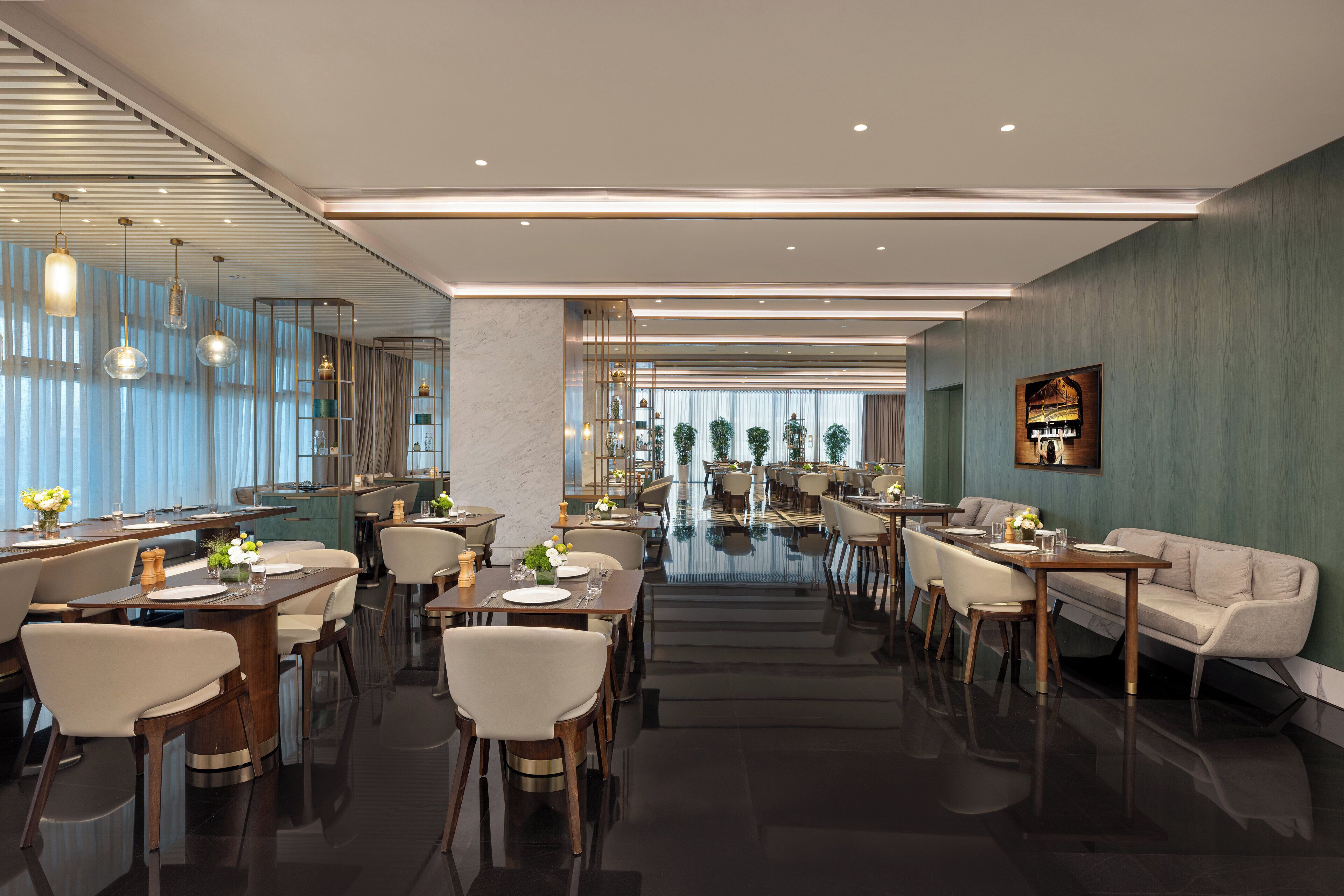 A modern hotel lobby with a central reflective pool, dining area with tables and chairs, and a seating area with sofas.