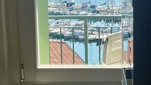 Une vue depuis une fenêtre donnant sur une marina, avec des bateaux et, au loin, une chaîne de montagnes.