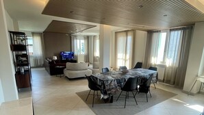 Un vaste espace de vie comprenant une table à manger, des canapés et un téléviseur.