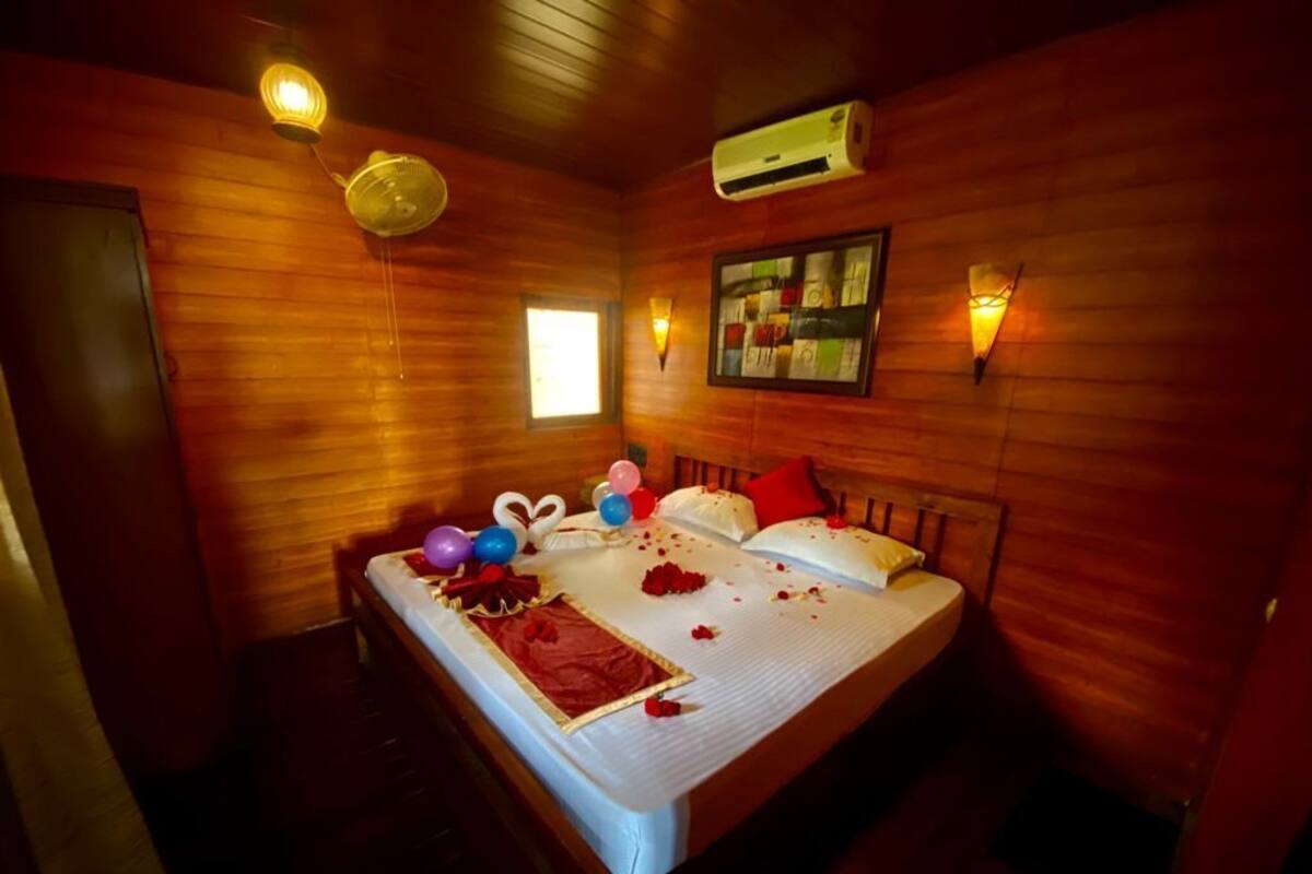 Ein Zimmer mit Holzboden, einem Bett, Wandklimaanlage und einem gerahmten Bild.