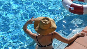 Une piscine avec une eau d’un bleu limpide, une bouée de sauvetage et une serviette posée sur le bord.