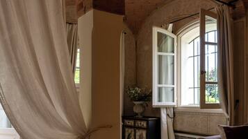 Una habitación con cama, sofá, ventana con cortinas y techo de ladrillo.