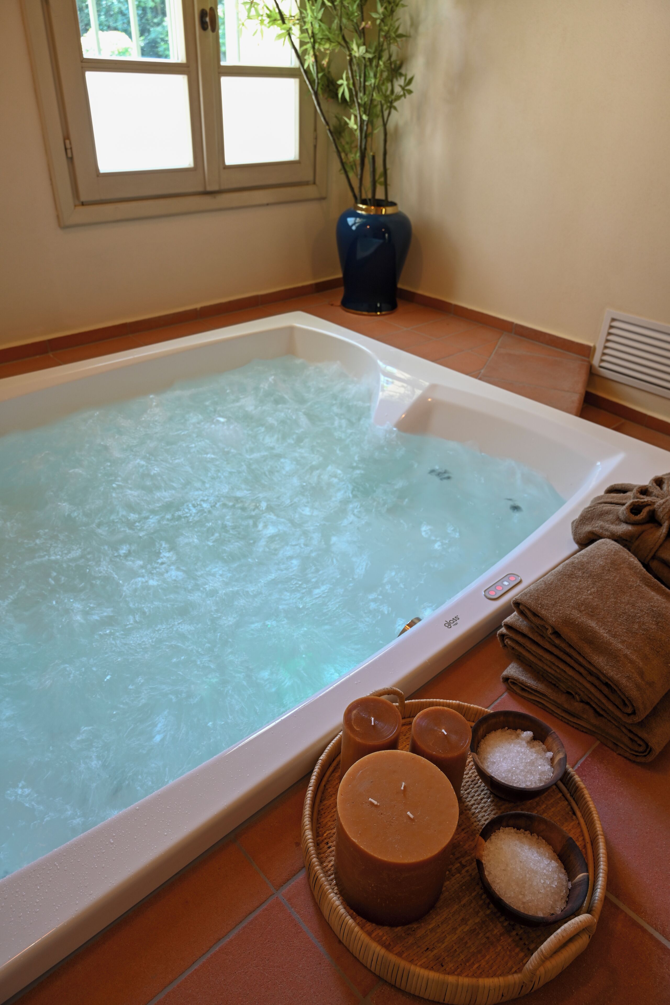 A spa bath with a control panel, towels, and bath salts.