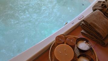 A spa bath with a control panel, towels, and bath salts.