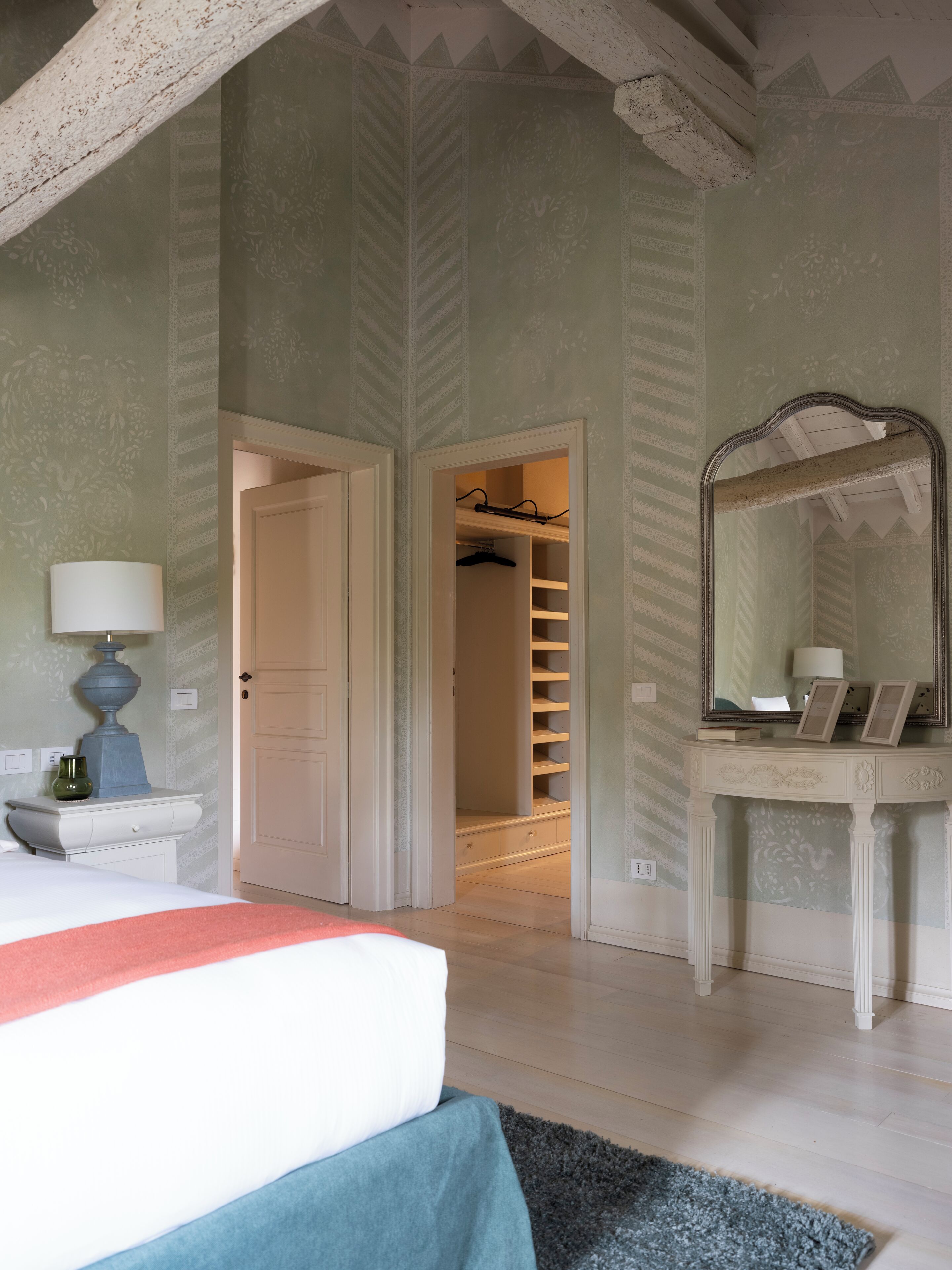 Ein Schlafzimmer mit einem Bett, einem Schminktisch, einem Spiegel und einem begehbaren Kleiderschrank.