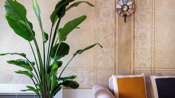 Una habitación con una planta grande en maceta, un muro decorativo y un sofá con cojines.