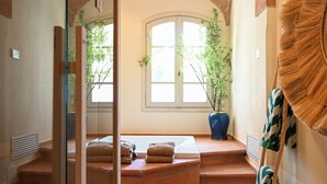 Una stanza con soffitto in mattoni, una grande finestra con vista, una pianta in vaso e una scala appoggiata al muro.