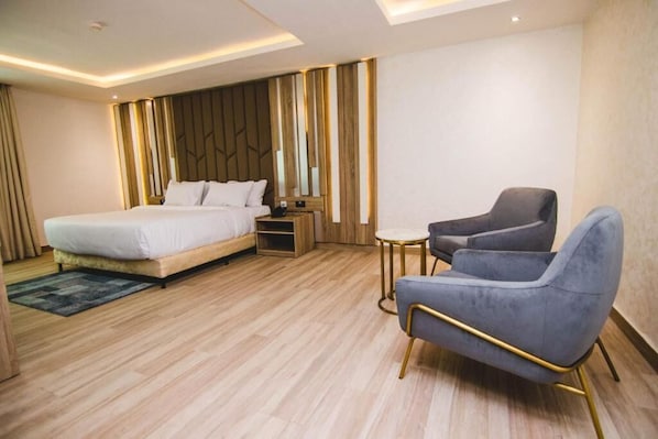 A modern hotel room with a bed, a seating area, and a nightstand. - The Safron Hotel Ikeja (Lagos)
